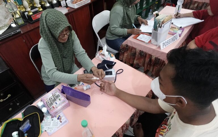 A Posbindu health worker conducting blood glucose testing as part of early detection and prevention efforts in Indonesia's battle against chronic diseases at a local healthcare facility in Tangerang, Banten, Indonesia.