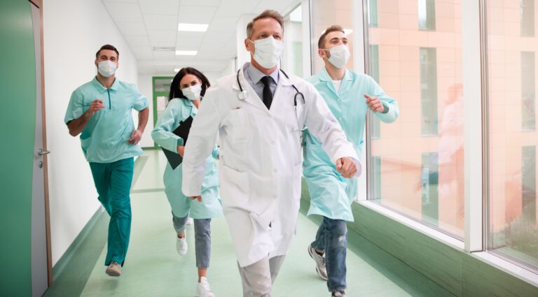 Healthcare team urgently responding to pediatric emergency in hospital corridor, illustrating real-time application of Pediatric Early Warning Score (PEWS) for critical care escalation.