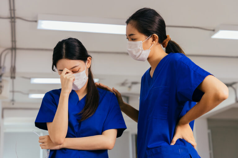 Nurse comforting a stressed colleague, illustrating the need for conflict resolution in healthcare.