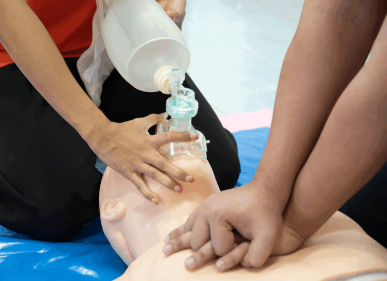 Healthcare workers practicing CPR on a training manikin using a bag valve mask during emergency life support training